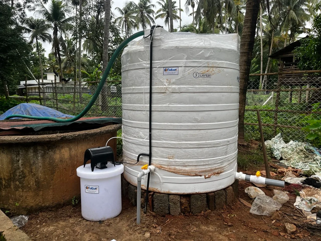 Treated-water storage tank and chemical dosing tank installed beside an open well at a Kerala property